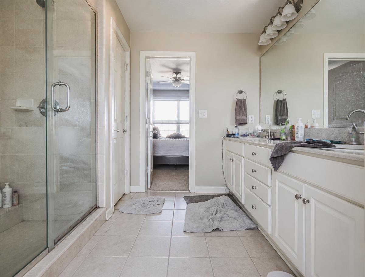 Bathroom before cleaning with a cluttered vanity and rumpled towels